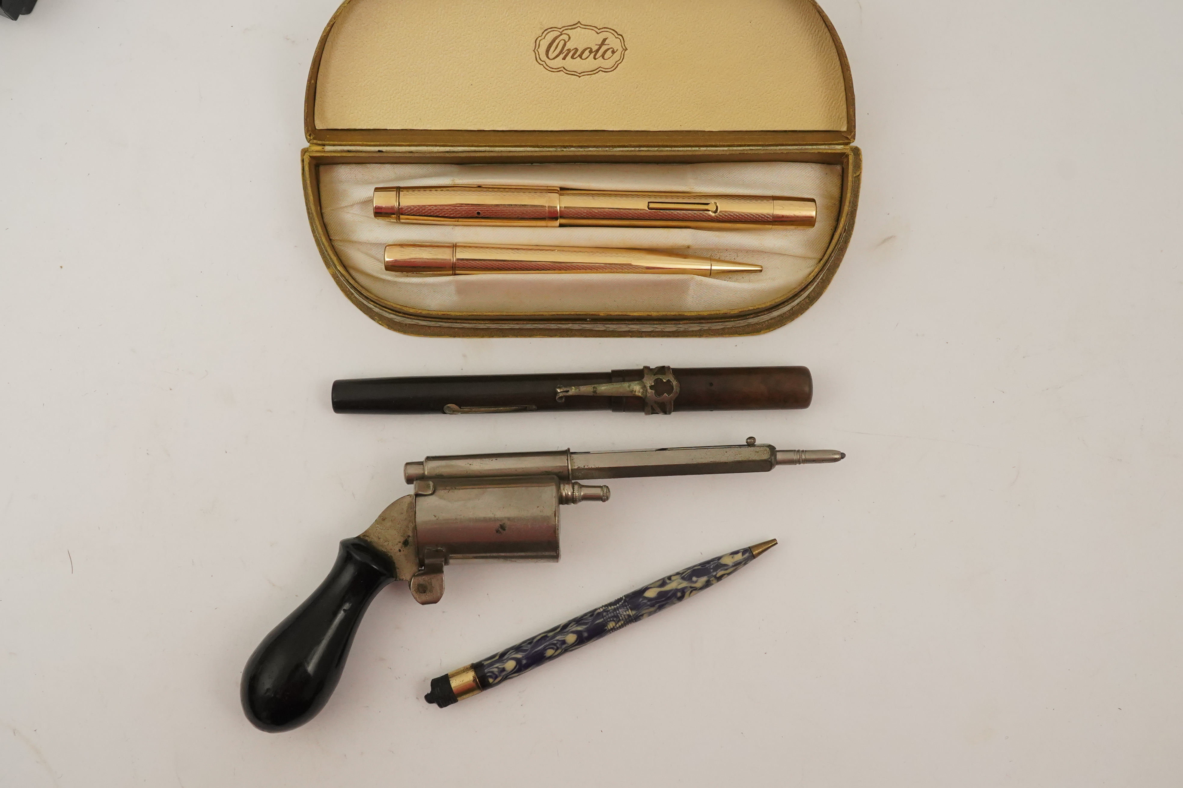 A novelty gun propelling pencil, a gold plated De La Rue Onoto fountain pen and matching pencil, in original box and two other items